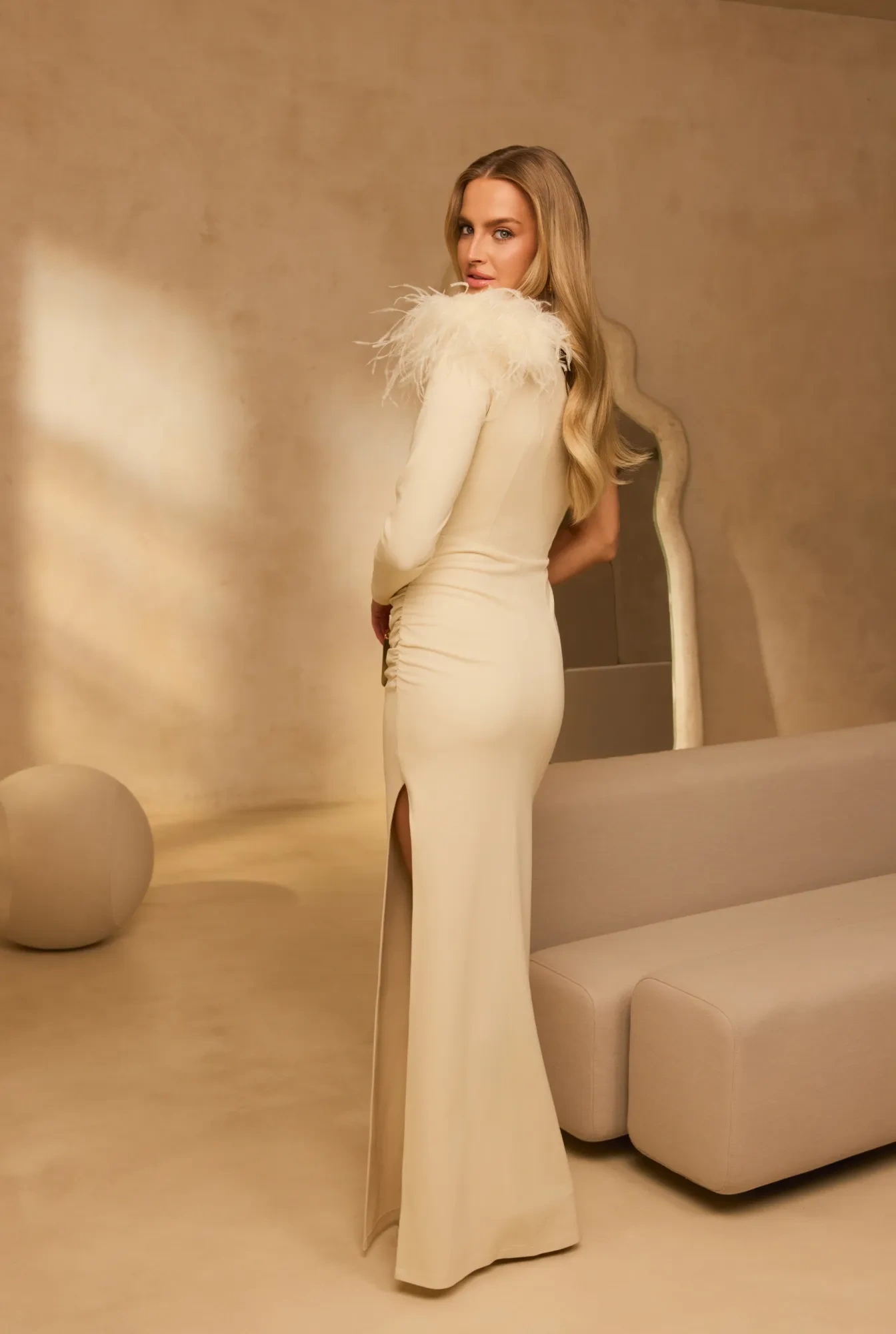 Elegante – abito maxi asimmetrico color ecru con spilla in piume